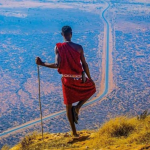 a man standing on a cliff looking at a road